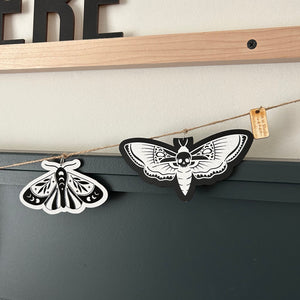 two laser cut moths and hanging from a jute twine garland
