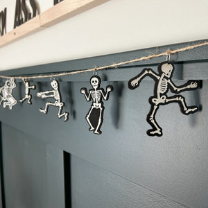 skeleton garland hang on a wall with dark green paneling in the background