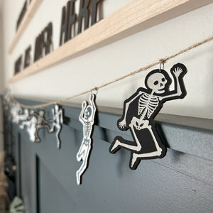 skeleton garland hangs on a paneled wall with each in a different pose
