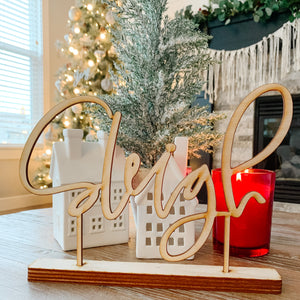 The word "sleigh" cut in natural wood standing on a coffee table in front of christmas decor