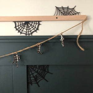 skeleton garland hangs on letterboard rail above a dark green paneled wall. laser cut spider webs are placed in corners