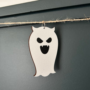 laser cut scary fanged ghost hanging from a jute twine string