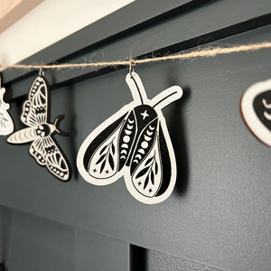 laser cut and hand painted moths hanging from a silver finding on jute twine string