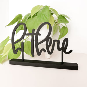 The phrase "hi there" in black standing on a white background. There is a neon pathos in the background adding some depth and color.