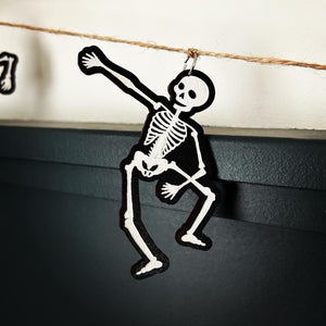 skeleton hanging from just twine with a silver finding in a dabing pose